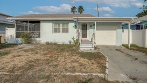 A single-story house with a garage, a front porch, and a small front yard. - Steps to Madeira Beach! Modern Family Getaway (Madeira Beach)