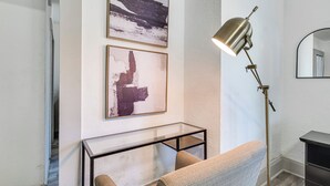 A modern room with a glass coffee table, a sofa, a floor lamp, and abstract wall art. - Walk to Winter Haven Hospital: Convenient Apt (Winter Haven)