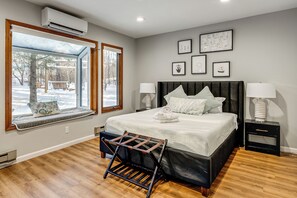 A bedroom with a large bed, two bedside tables with lamps, a window seat with a drying rack, and framed artwork on the wall. - Hot Tub + Game Room: Spacious Poconos Escape! (Tobyhanna)