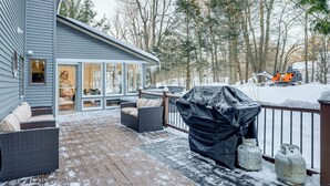 Une terrasse couverte, aménagée avec du mobilier d’extérieur, un barbecue et des bouteilles de propane.