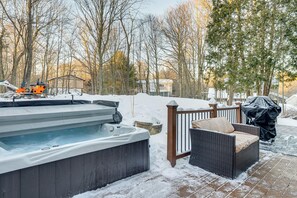 A hot tub with a wooden deck, a wicker chair, and a covered grill area. - Hot Tub + Game Room: Spacious Poconos Escape! (Tobyhanna)