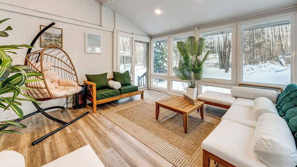 Un salon chaleureux avec un fauteuil à bascule, un canapé vert, un divan blanc et une table basse en bois.