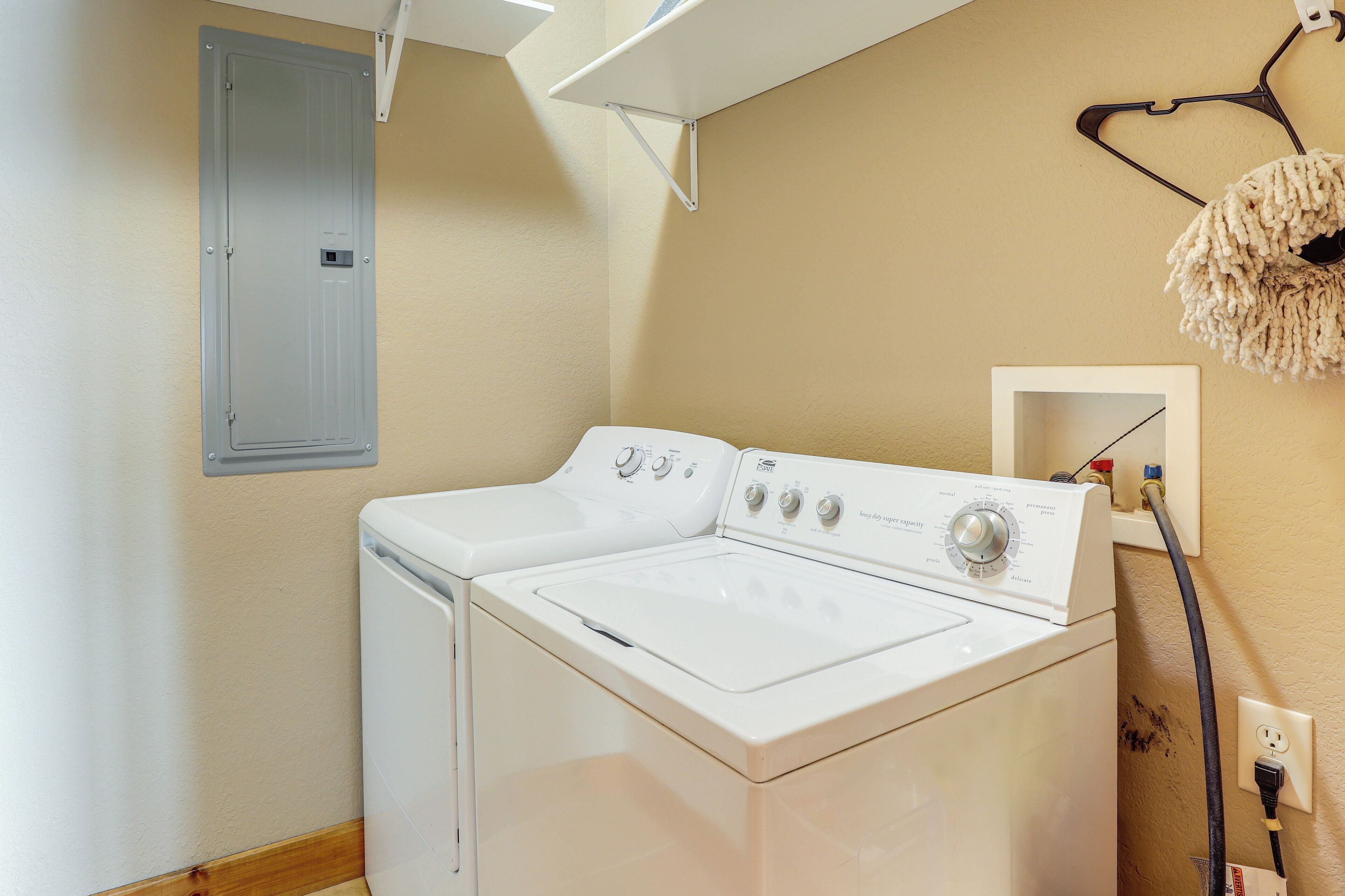 Une buanderie équipée d’un lave-linge et d’un sèche-linge à chargement frontal, d’une prise de courant et d’un luminaire fixé au mur.