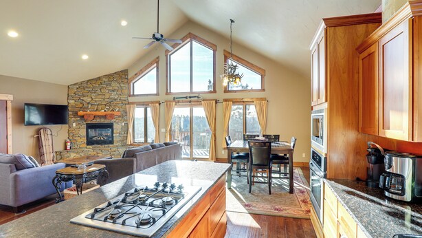 A spacious kitchen with a central island, wooden cabinets, and a stone accent wall. - 1 Mi to Terry Peak! Black Hills Cabin Hideaway (Lead)