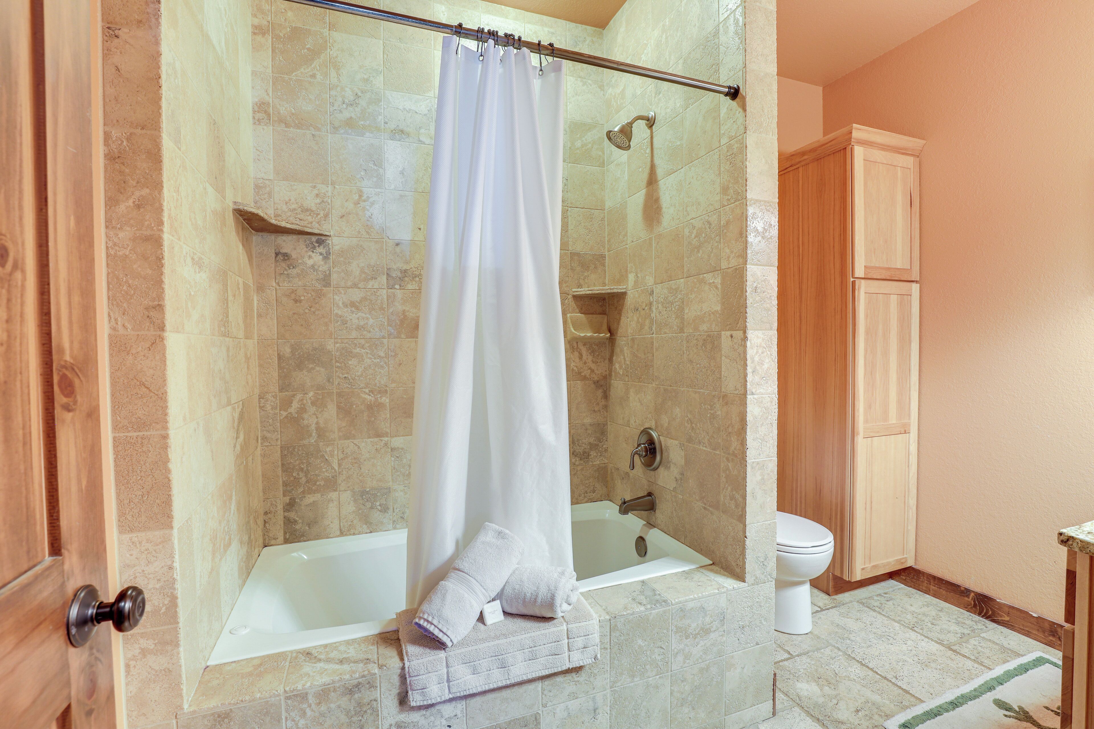A bathroom with a glass-enclosed shower, a bathtub, and a toilet.