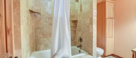 A bathroom with a glass-enclosed shower, a bathtub, and a toilet.
