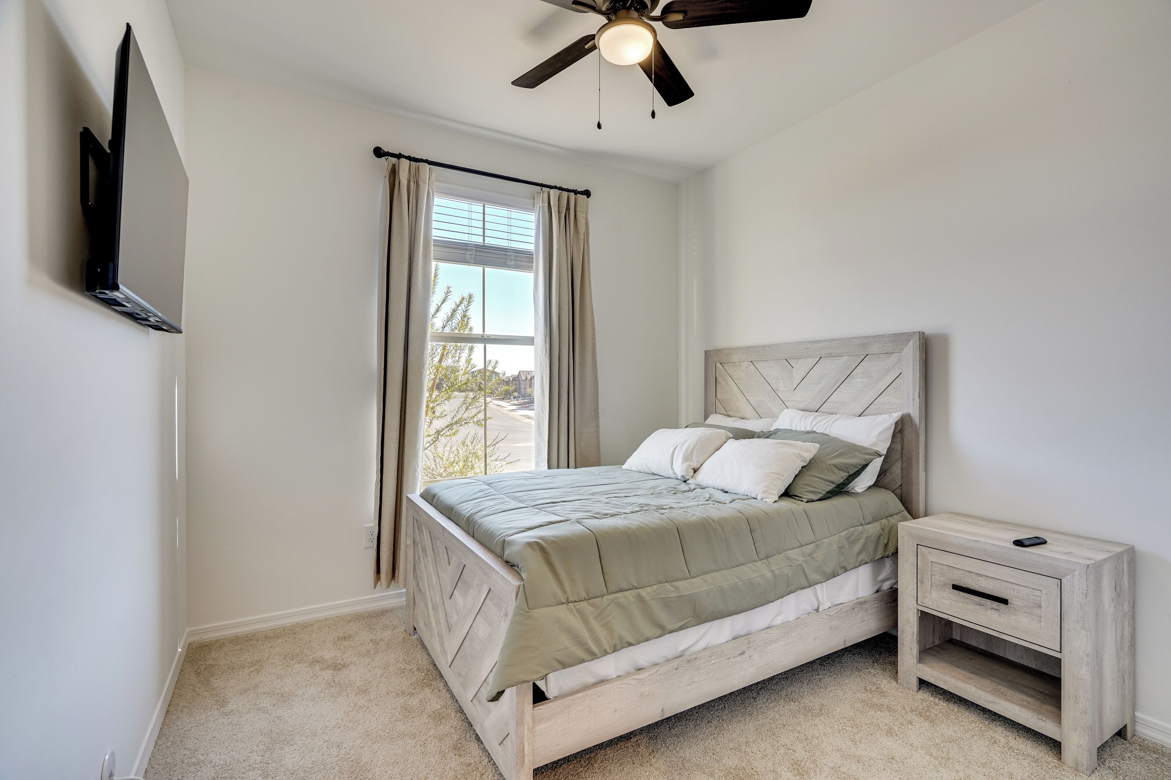 A bedroom with a bed, nightstand, and ceiling fan.