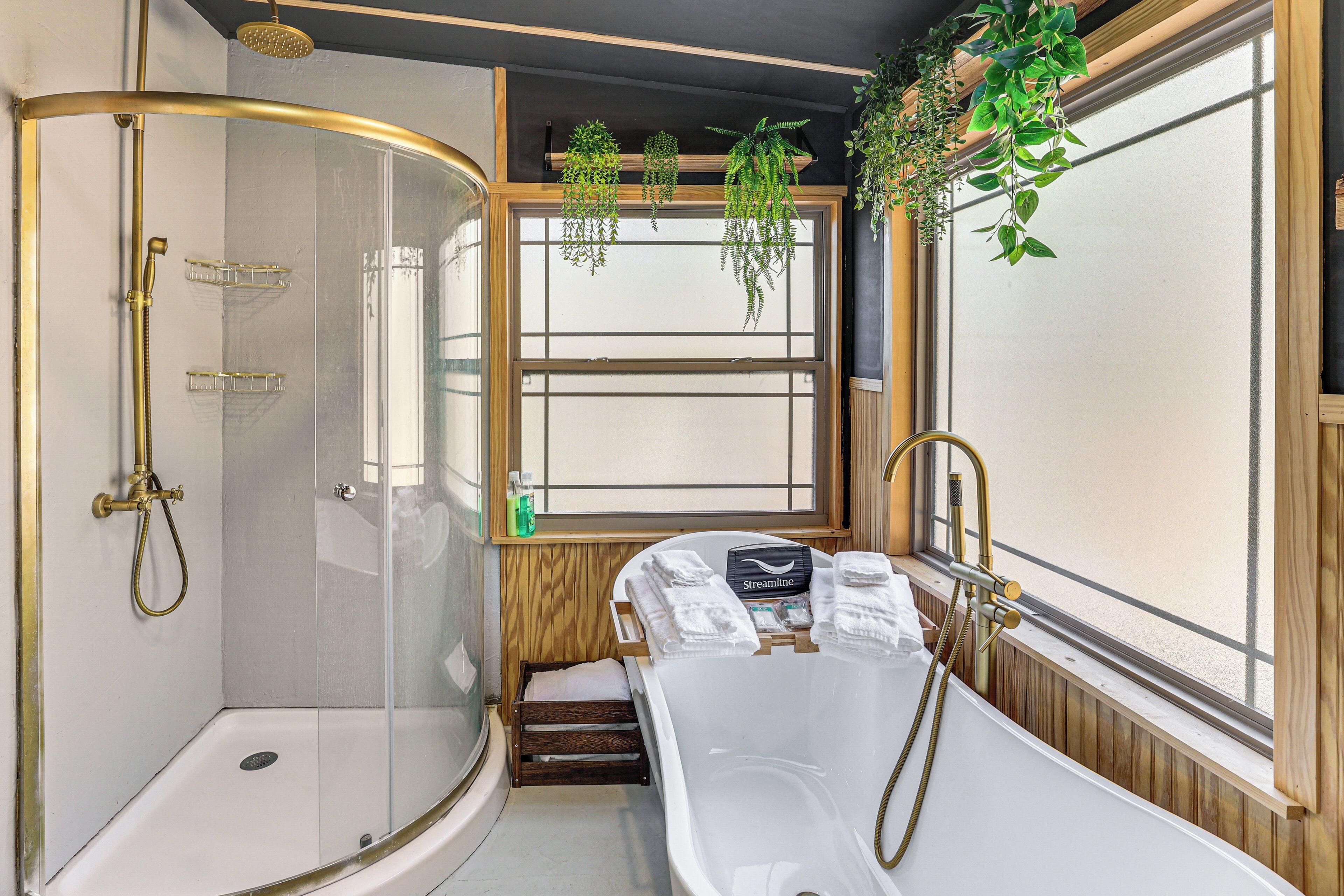 A modern bathroom with a glass-enclosed shower, a freestanding bathtub, and wooden accents.