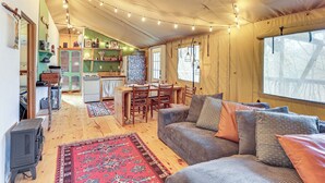 A cozy living room with a sofa, a rug, and a dining area with chairs and a table. - 16 Mi to Lookout Mtn: Glamping Tent w/ Hot Tub (Trenton)