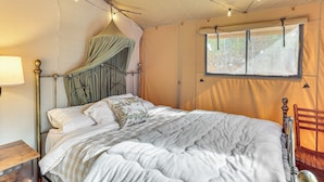 A bed with a canopy, a wooden nightstand, a window with a view, and a chair. - 16 Mi to Lookout Mtn: Glamping Tent w/ Hot Tub (Trenton)