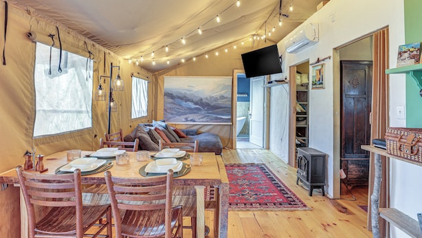 A cozy interior with a dining area, wooden furniture, and a large window with curtains. - 16 Mi to Lookout Mtn: Glamping Tent w/ Hot Tub (Trenton)