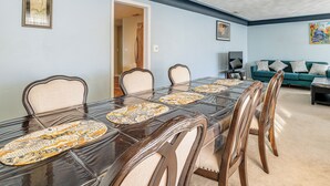 Een eetruimte met een lange tafel, stoelen en een blauwe bank.