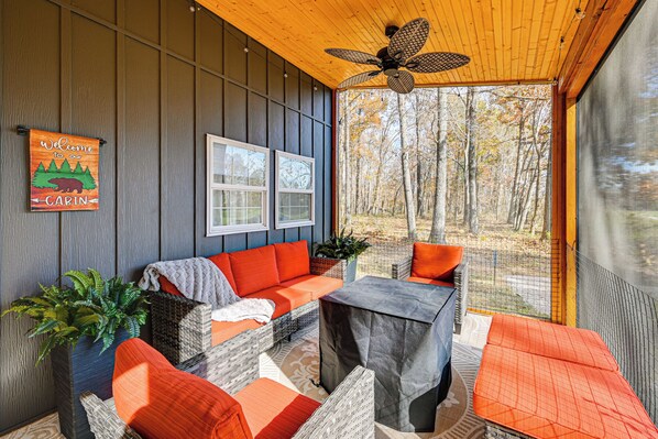 A cabin interior with a wooden ceiling, a ceiling fan, wicker furniture, and a view of autumn trees. - 4 Mi to Mammoth Cave: Hand-built Cabin on 70 Acr (Brownsville)