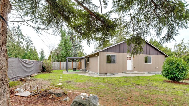 A single-story house with a brown exterior, a covered porch, and a well-maintained lawn. - Puget Sound Single-level Gem w/ Outdoor Fun! (Puyallup)