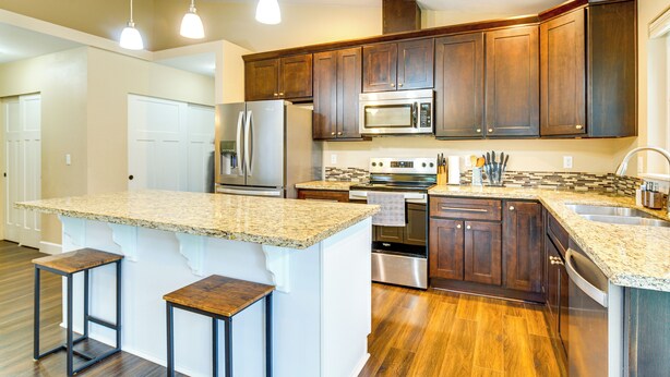 A modern kitchen with granite countertops, stainless steel appliances, and wooden cabinets. - Puget Sound Single-level Gem w/ Outdoor Fun! (Puyallup)