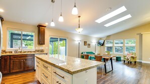 A spacious kitchen with granite countertops, wooden cabinets, and pendant lighting. - Puget Sound Single-level Gem w/ Outdoor Fun! (Puyallup)