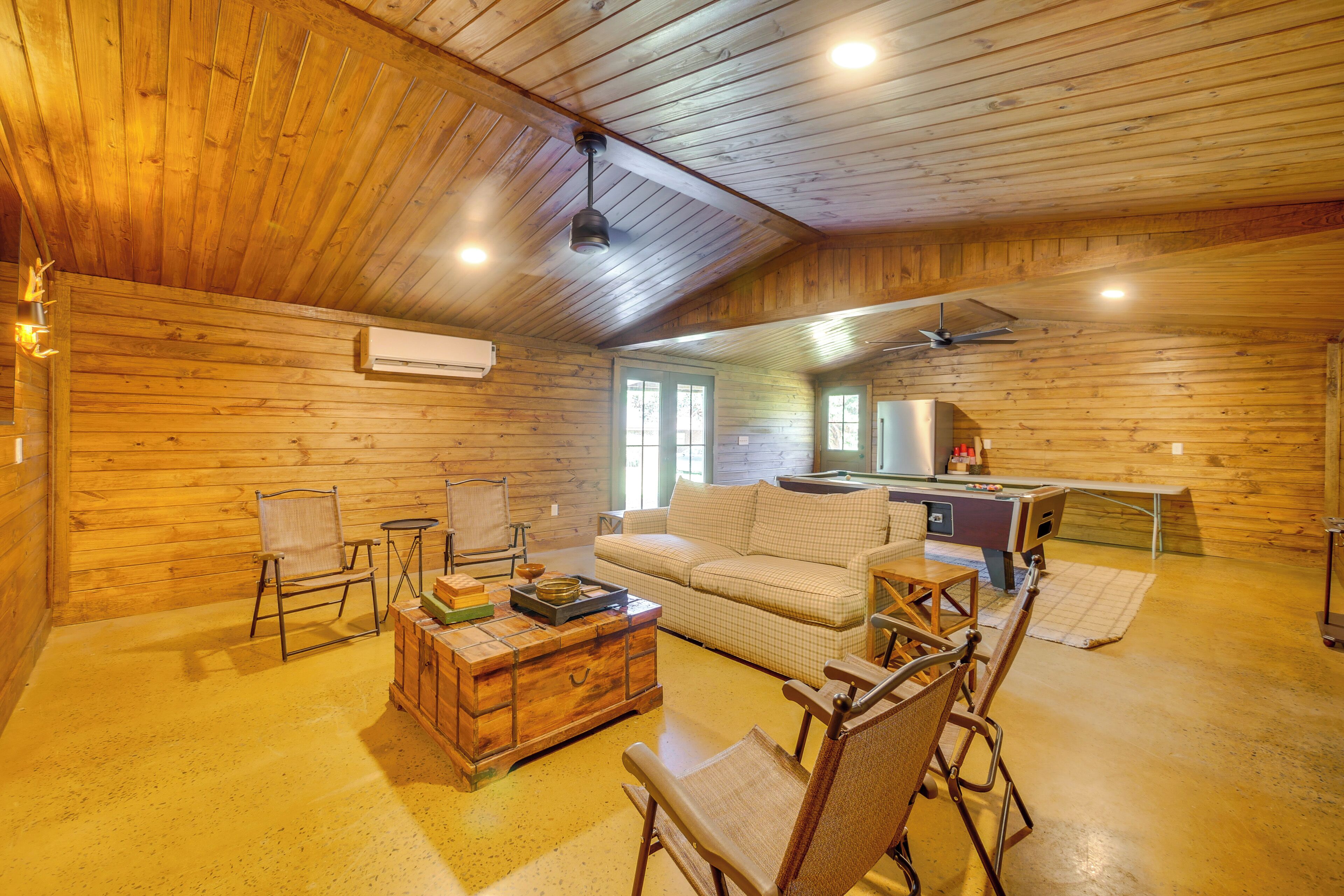 A wooden interior with a sofa, chairs, a coffee table, and a small kitchen area.