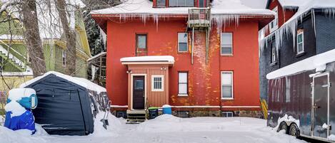 Una casa roja con un garaje negro y una tienda de campaña azul en la nieve.