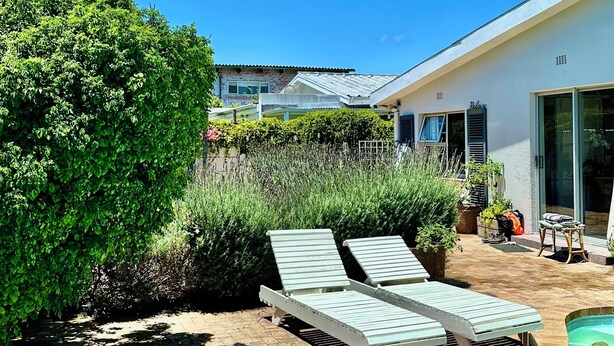 A modern house with a swimming pool, two lounge chairs, and a well-maintained garden. - SurfWay beach cottage - Your Cape beach getaway (Cape Town)