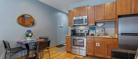 Una cocina compacta con armarios de madera, un refrigerador de acero inoxidable y un horno empotrado.