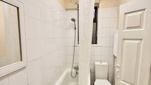 A bathroom with white tiled walls, a bathtub, a shower, and a toilet. - 3bedroom Entire House in Stockport Town Manchester (Stockport)