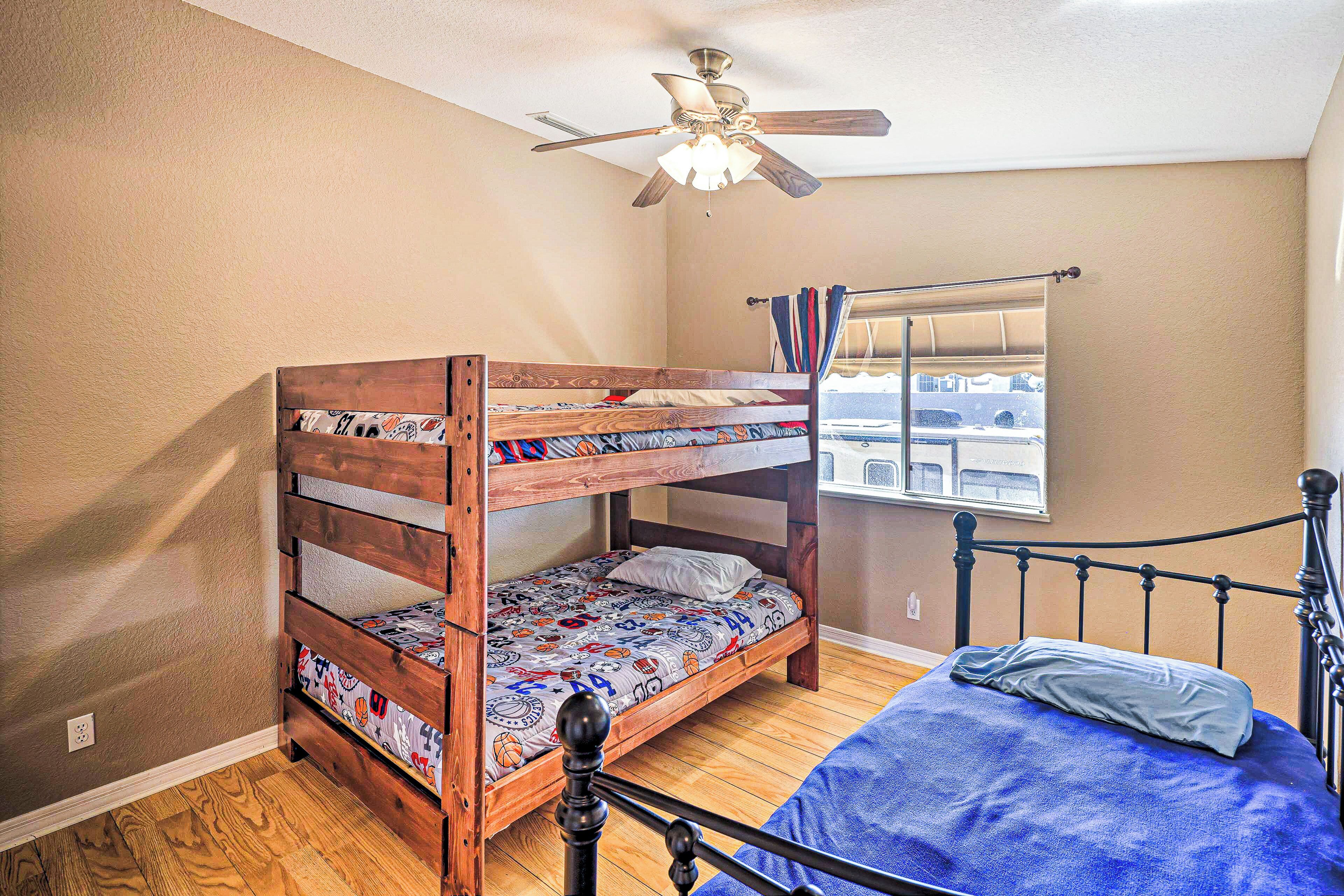 A bunk bed with a ceiling fan, a window with curtains, and a view of a building outside.