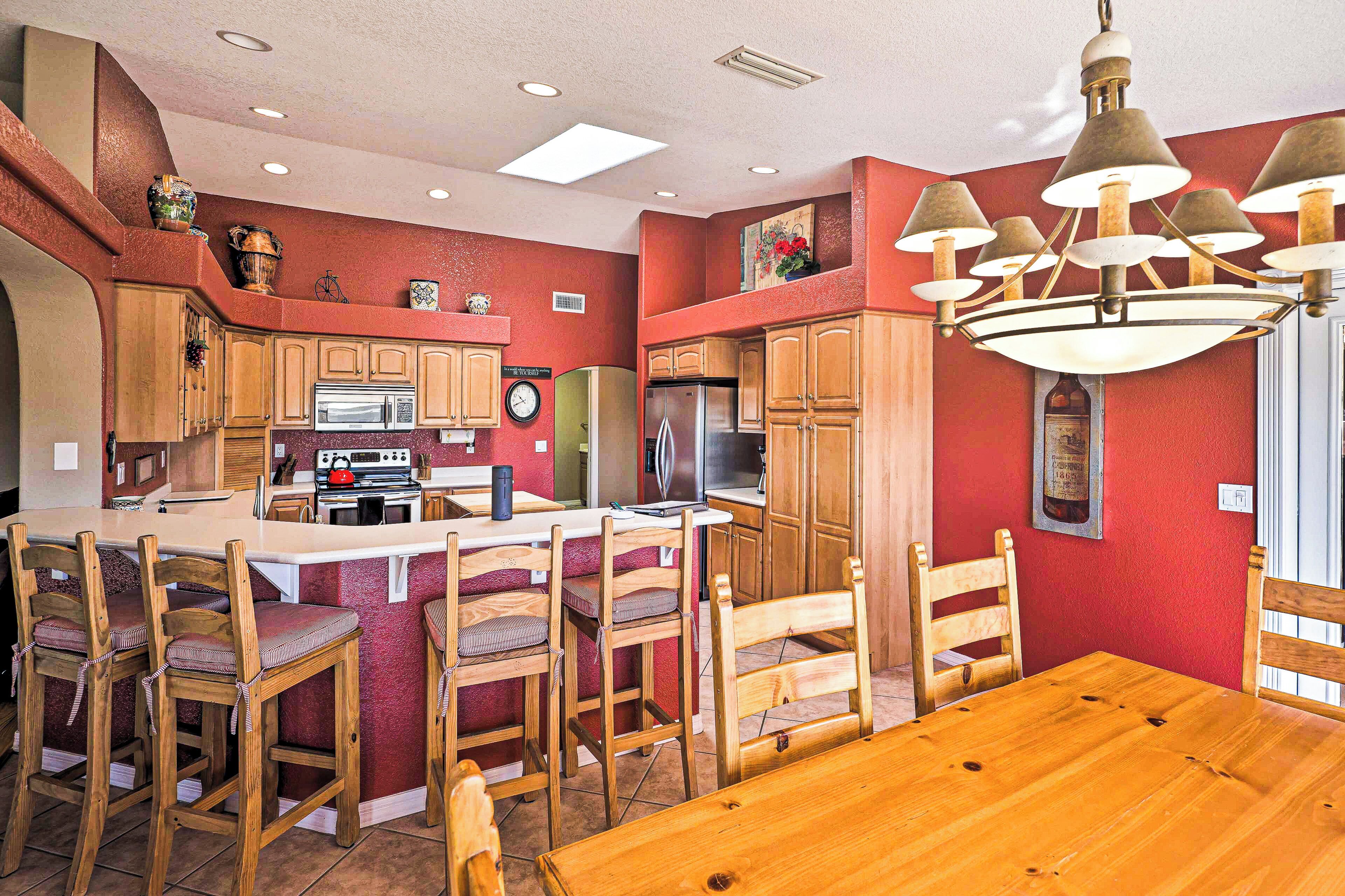 A kitchen with wooden cabinets, a central island with bar stools, and a chandelier.