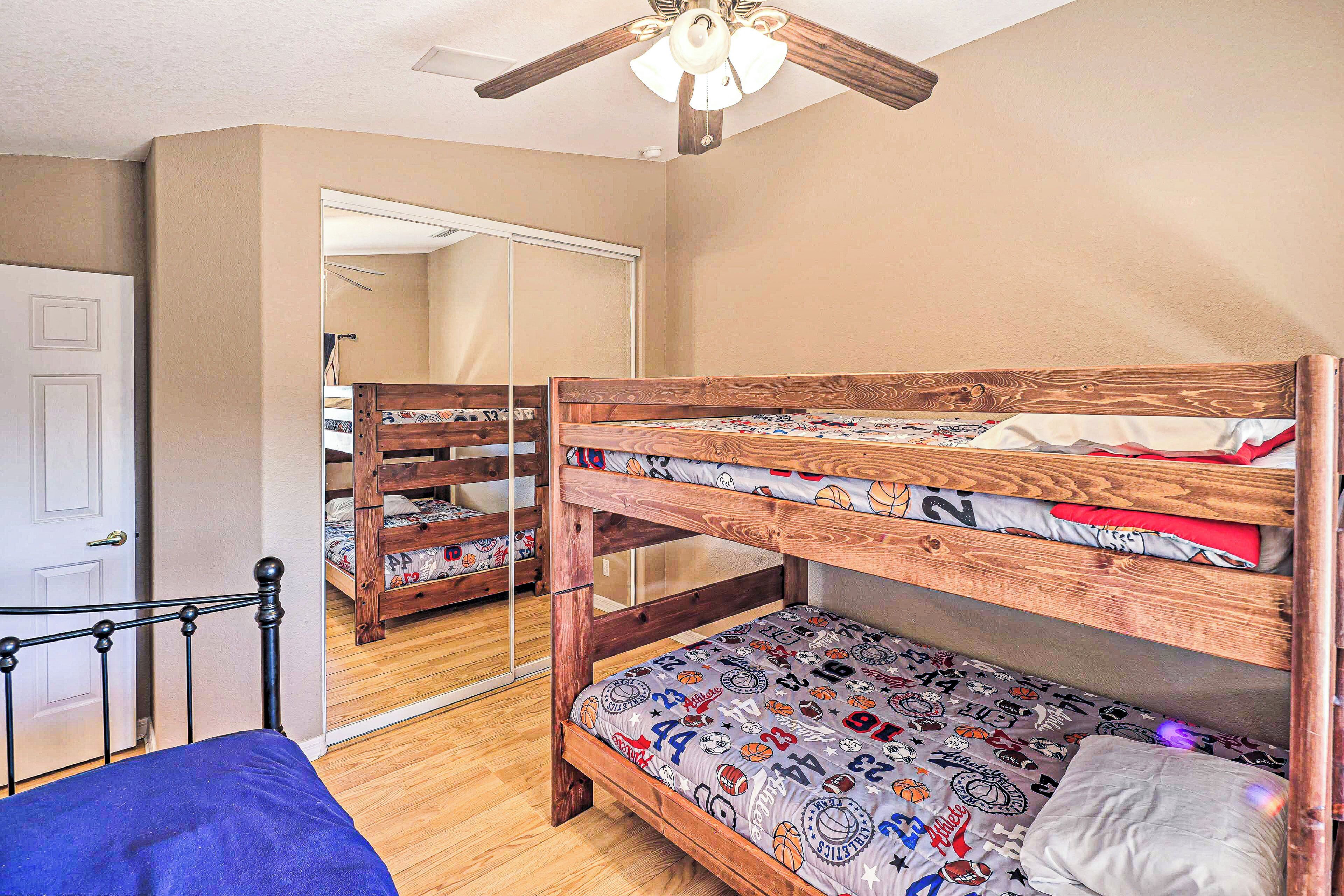 Ein Zimmer mit Etagenbett, Holz-Kopfteil und Deckenventilator.