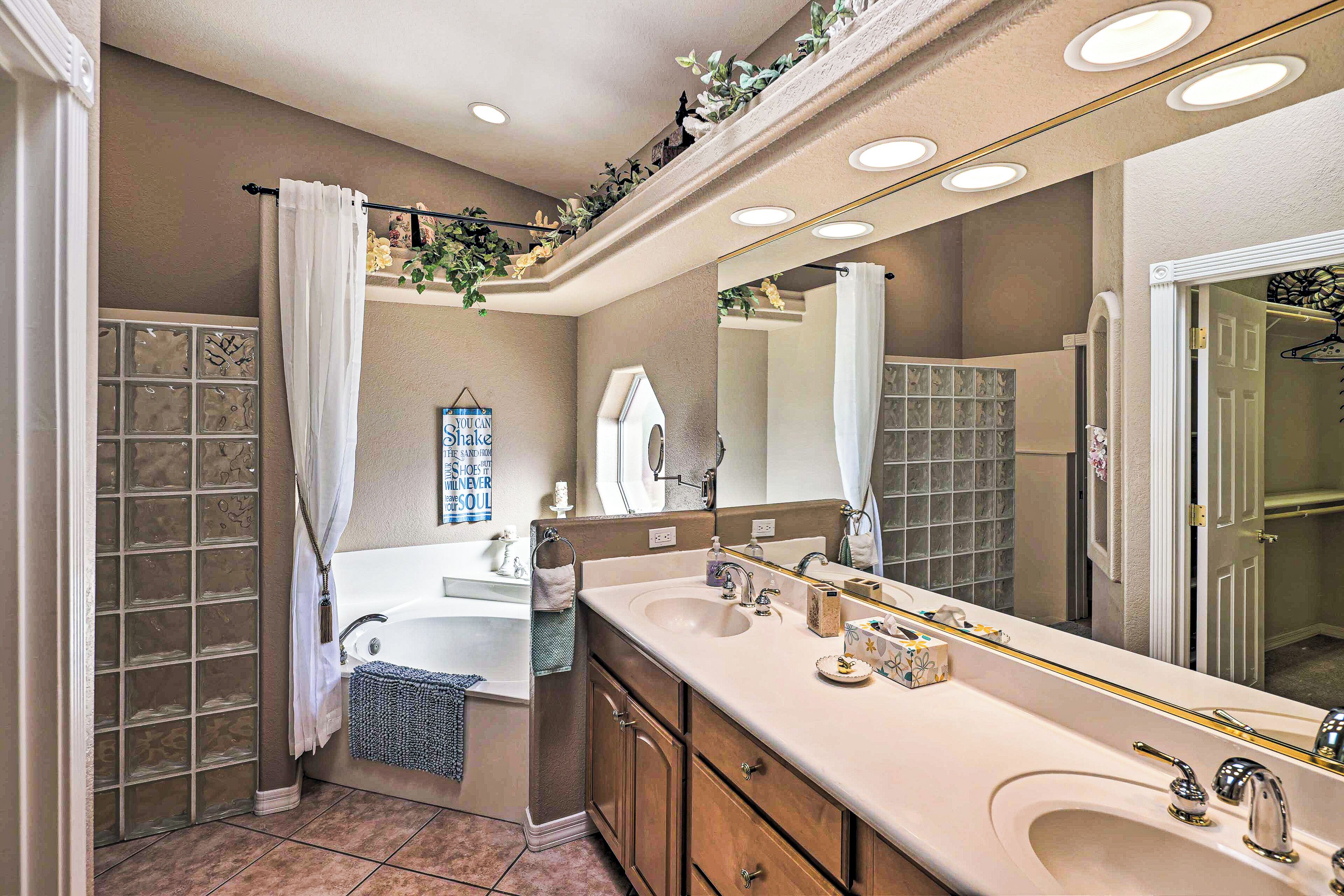 A bathroom with a large mirror, a bathtub, and a shower area.