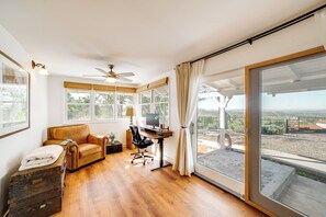 A spacious room with a wooden floor, a leather sofa, a desk with a computer, and large windows offering a view of the outdoors. - Spacious Riverside Farmhouse, Perfectly Located (Riverside)