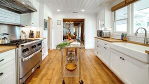 Eine moderne Küche mit einem Edelstahlherd, weißen Schränken und einer Holzausziehtafel.
