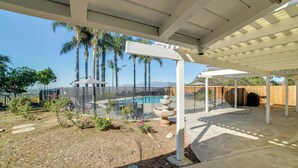 Ein überdachter Patio-Bereich mit Pool, Palmen und Blick auf Berge.