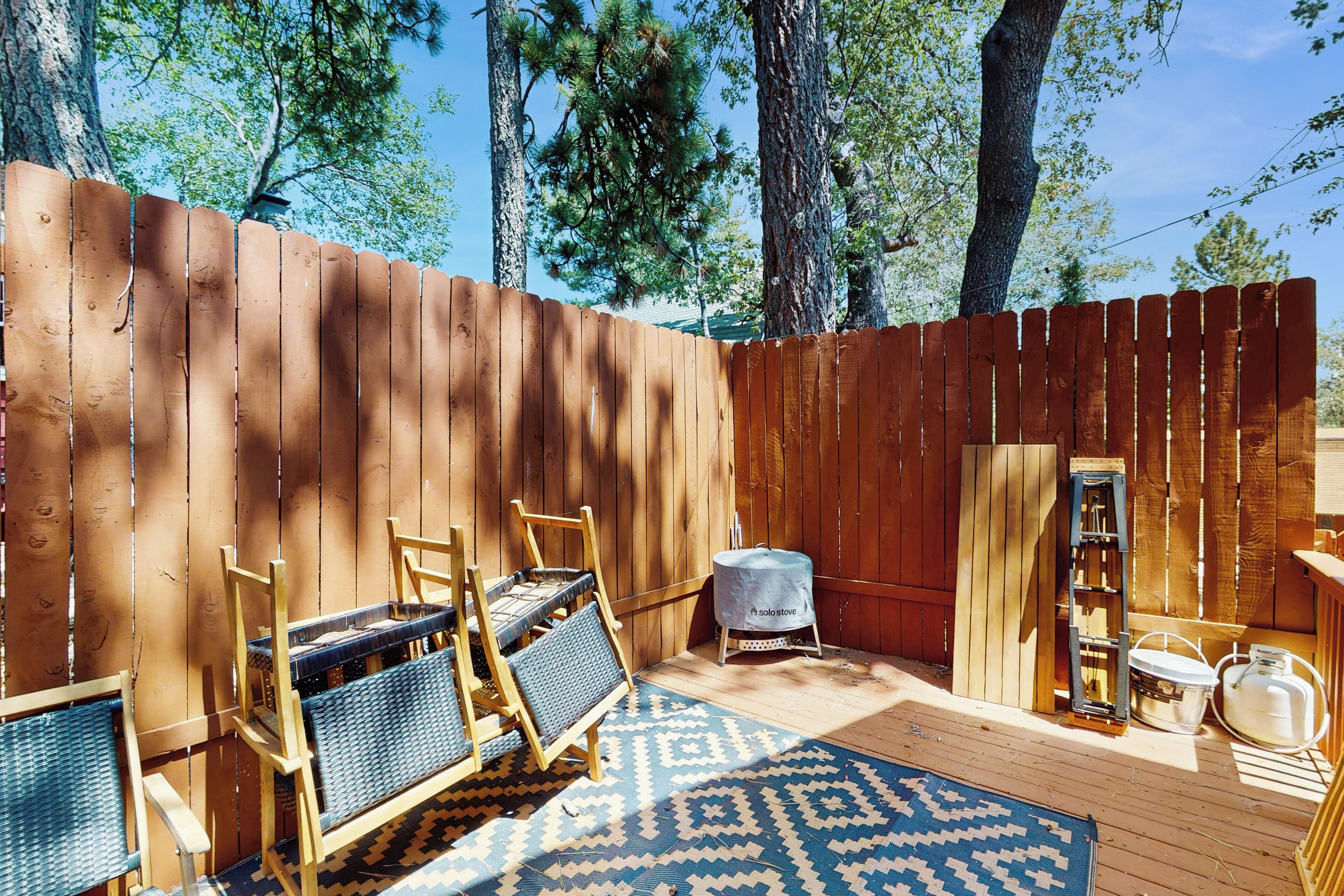 Una terraza de madera con mobiliario exterior, una parrilla y un tapete estampado.