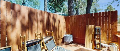 Una terraza de madera con mobiliario exterior, una parrilla y un tapete estampado.