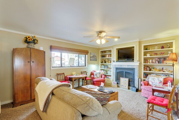 A living room with a sofa, chairs, a coffee table, a fireplace, and a bookshelf. - 6 Mi to Dtwn Fort Collins: Cozy Apt w/ Shared Yard (Fort Collins)