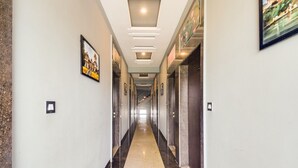 A long, narrow hallway with a polished floor and framed pictures on the walls. - Hotel Maanvad Garh by Keshav Residency (Udaipur)