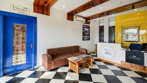 A reception area with a blue door, a brown sofa, a checkered floor, and a reception desk with a yellow accent wall. - Hotel Maanvad Garh by Keshav Residency (Udaipur)