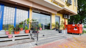 A building entrance with a glass door, potted plants, and a red generator on the steps. - Hotel Maanvad Garh by Keshav Residency (Udaipur)