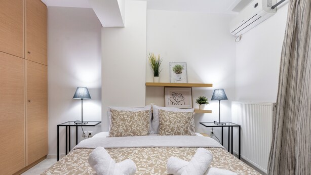 Ein modernes Schlafzimmer mit einem Bett, zwei Nachttischen, einem Beistelltisch, einem Regal mit Pflanzen und einer Heizung.
