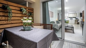 Ein modernes Wohnzimmer mit Esstisch, Sofa und einer durch eine Schiebetür einsehbaren Küche.
