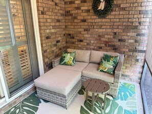 A corner seating area with a cushioned sofa, a wicker ottoman, and a small round table. - Beautiful 1st Floor, Pet Friendly Condo in Barefoot Landing  (North Myrtle Beach)