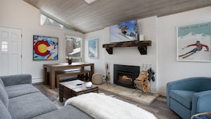 A modern living room with a fireplace, a large TV, and various artworks. - 929 Red Sandstone 3 Bedroom Condo (Vail)