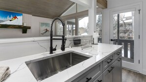 A modern kitchen with a large island, stainless steel sink, and a black faucet. - 929 Red Sandstone 3 Bedroom Condo (Vail)