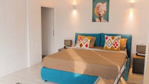 A bedroom with a bed, two bedside tables, a nightstand, a painting on the wall, and a door. - Penthouse with Rooftop next to the Park (București)