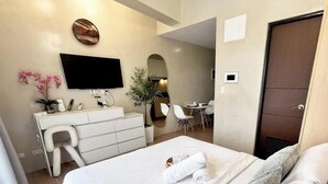 A hotel room with a bed, a desk, a chair, a television, and a mirror. - Room-stylish Studio Stay at Saint Domini (Iloilo)