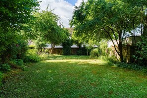 Ein üppiger Garten mit Steinmauer, Bäumen und blauem Himmel.