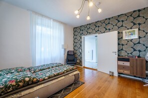 Une pièce comprenant un lit, une chaise, un bureau et une porte donnant sur une autre pièce.