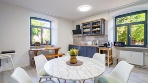 Een keuken met een ronde marmeren tafel, witte stoelen en een bloevas.