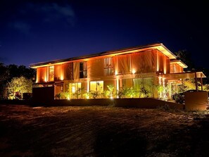 A modern two-story house with large windows and a well-lit exterior at night. - Nana's House. Comfort and exclusivity in the best condominium in Praia do Forte. (MATA DO SÃO JOÃO)