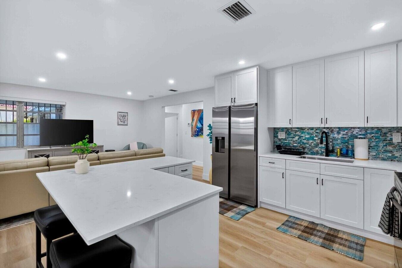A modern kitchen with white cabinets, a stainless steel refrigerator, and a tiled backsplash.